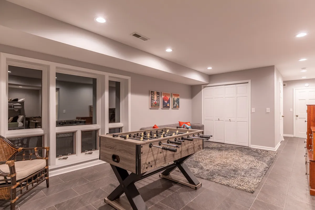 This image features a foosball table, artwork on the wall, and a comfortable seating area in a casual, social setting. The room looks lively and designed for group fun, aligning perfectly with the game's room vibe described in the section.
