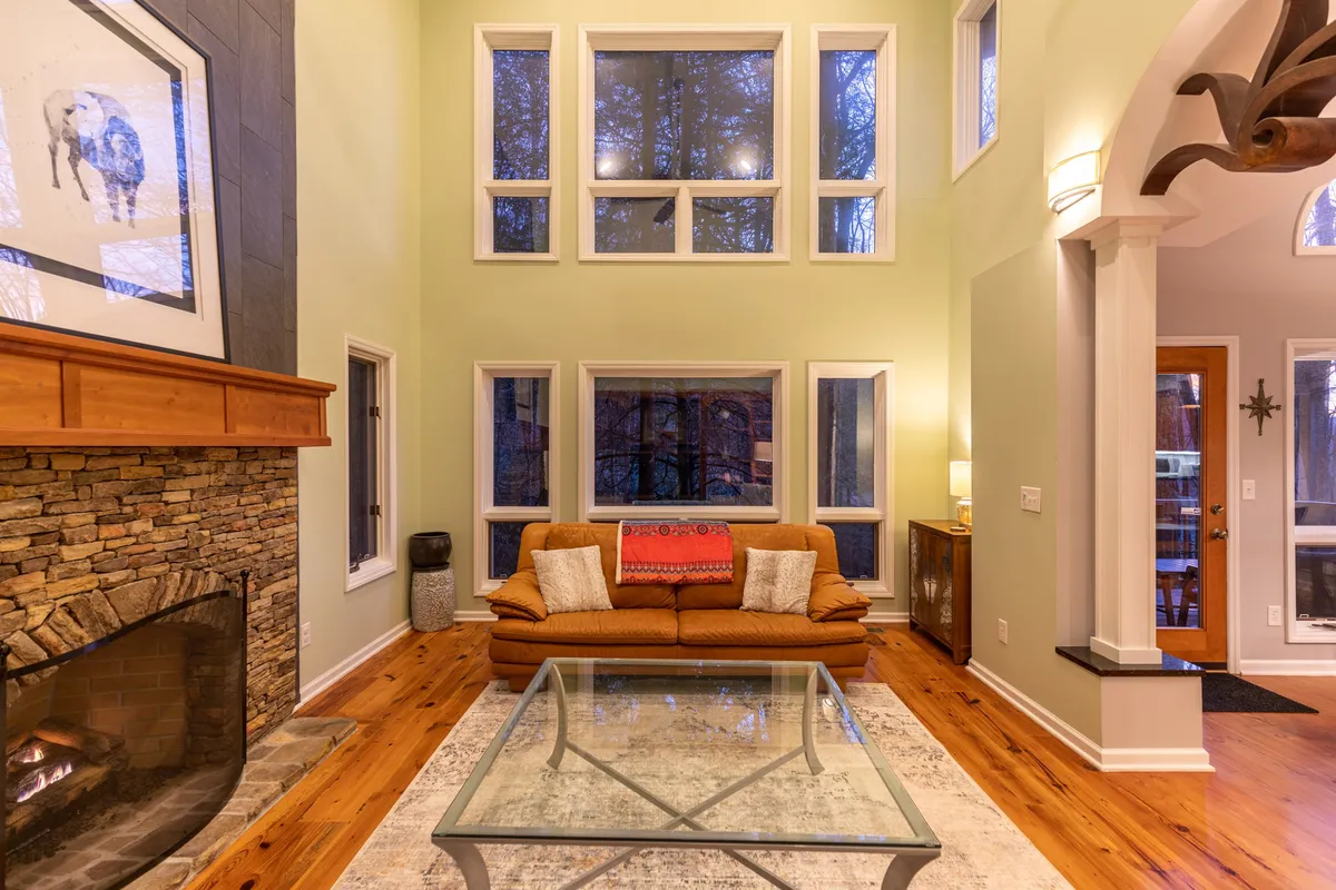 This image showcases a cozy living area with a fireplace, large windows that frame outdoor views, and comfortable seating. The scene is warm and welcoming, ideal for relaxing after a day of exploring nature and trails nearby.