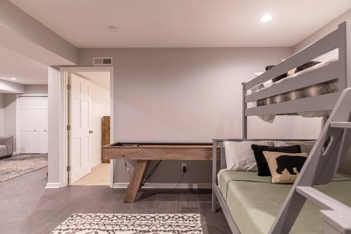 A playful, family-friendly interior scene featuring a bunk bed, pool table, and décor with a whimsical bear motif—perfect for kids and family gatherings after a day outdoors.